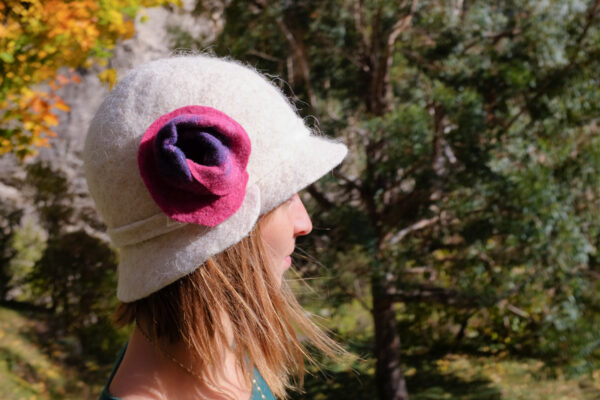 Femme portant un chapeau blanc en feutre avec une fleur rose