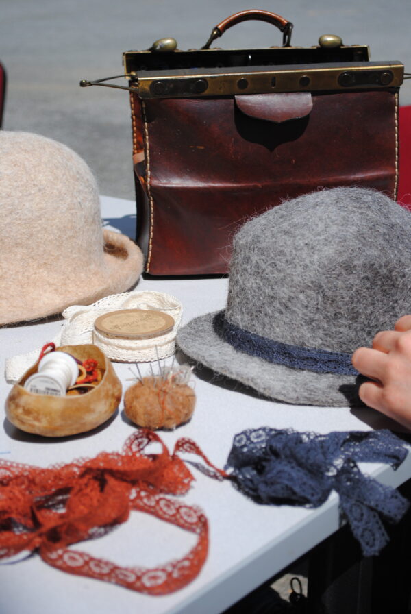 couture d'un ruban sur un chapeau en feutre dans l'atelier de la fée capeline